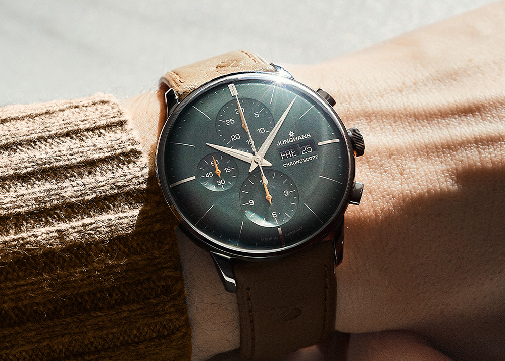 Steel cased chronograph watch with green dial on beige leather strap worn on a wrist