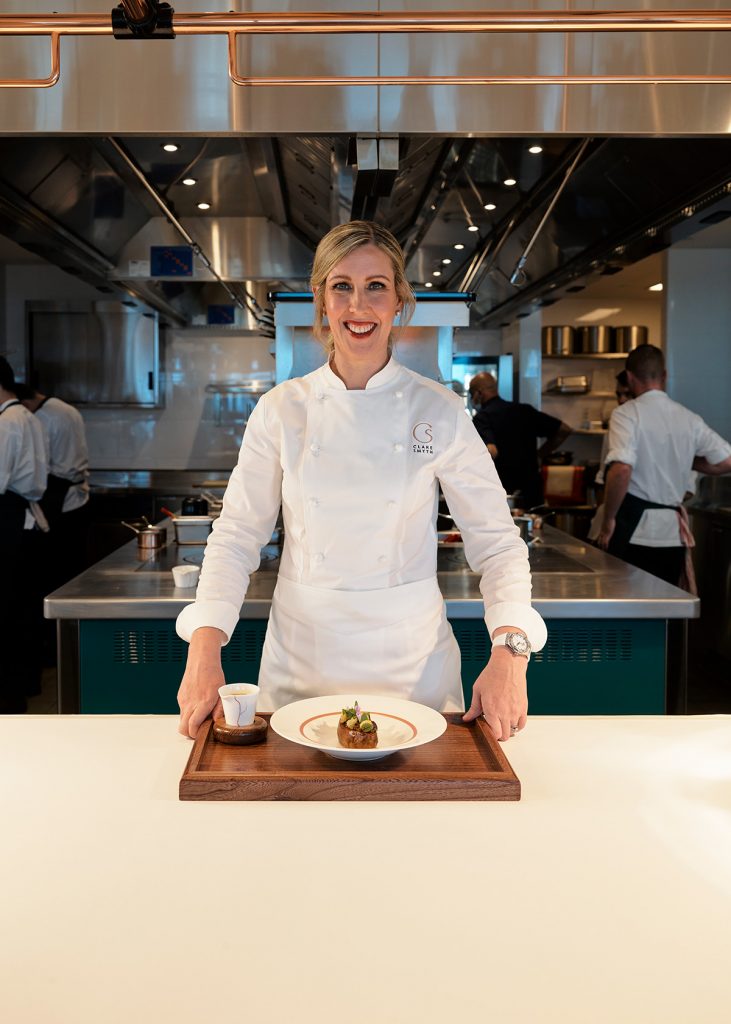 Clare Smyth at the kitchen pass presenting a dish