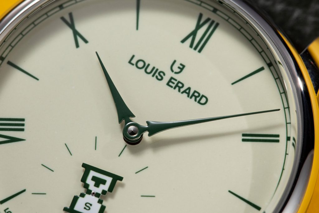 Close up of the green fir-shaped hour and minute hands, indices, Louis Erard logo against beige enamel dial