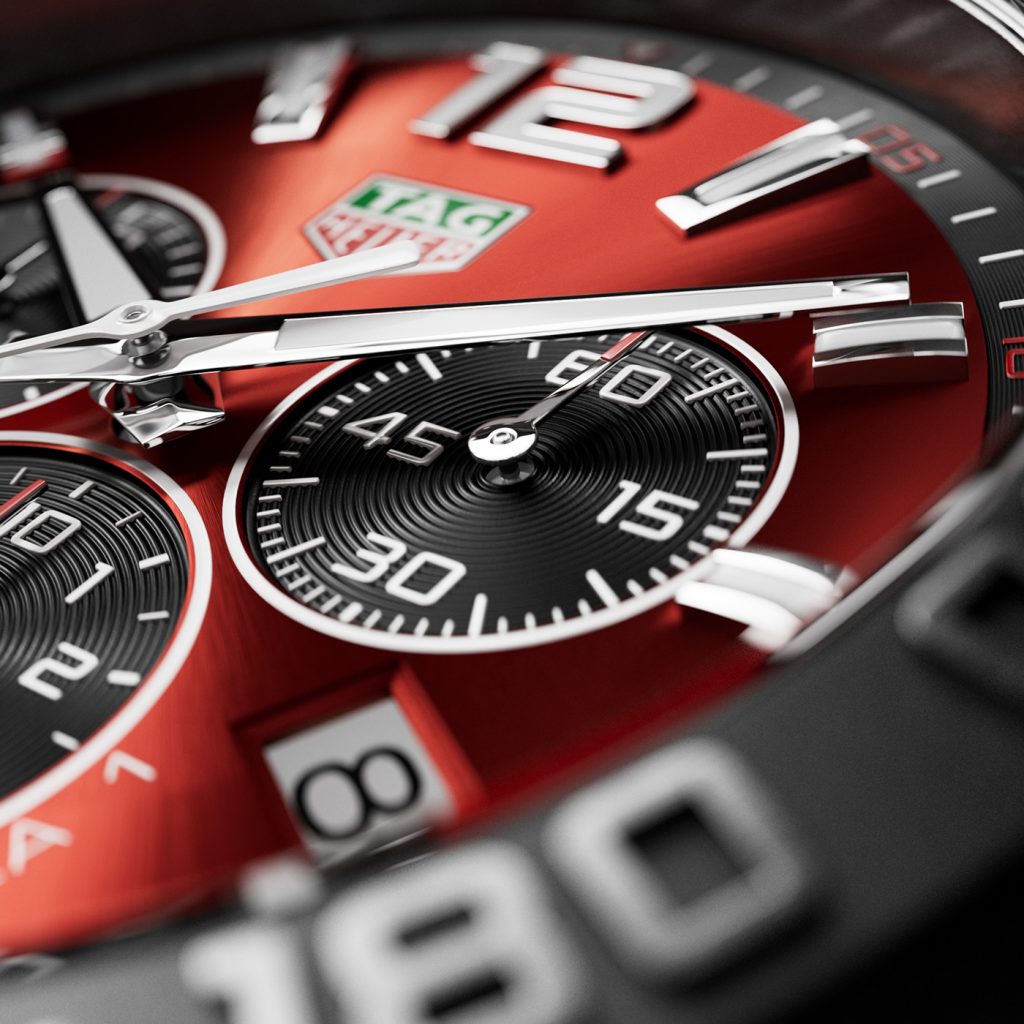 Close-up of a chronograph with red dial, white hands and indices, and black sub-counters