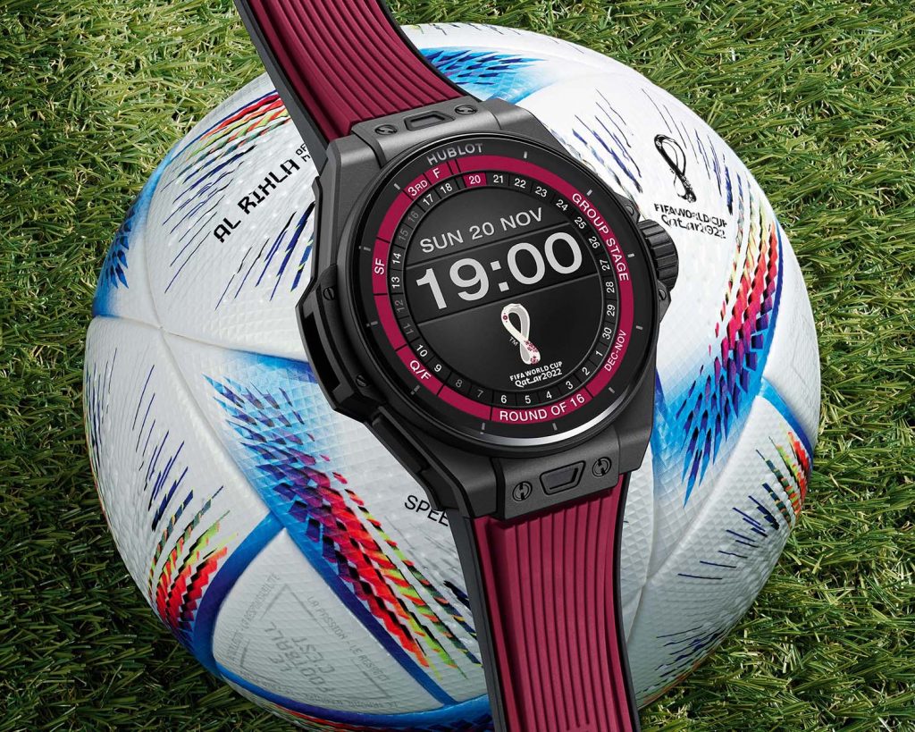 Connected watch with black ceramic case and burgundy rubber strap on a white decorated white soccer ball