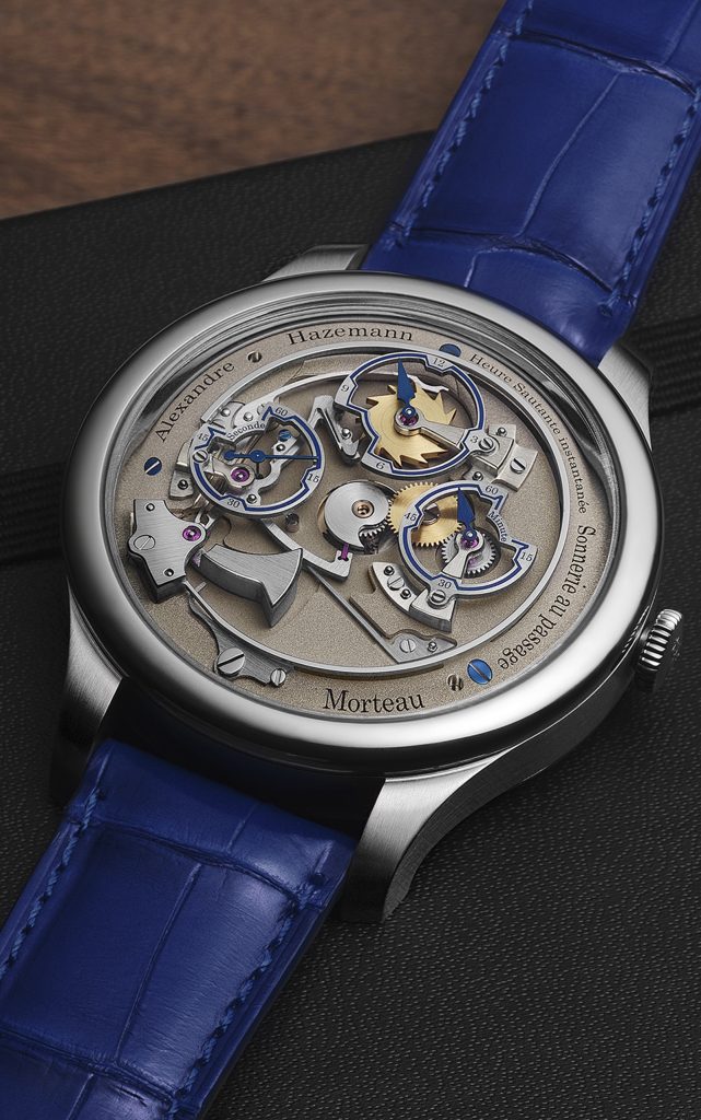 Close-up of Steel cased jumping chiming hour watch on blue leather strap surrounded by watch tools