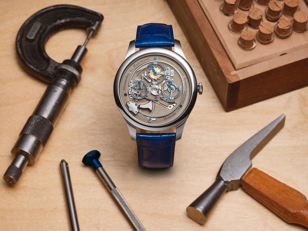 Steel cased jumping chiming hour watch on blue leather strap surrounded by watch tools